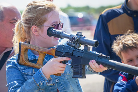 Samara, Russia - August 18, 2018: Woman with glasses holding a sniper rifle with a optical-sight