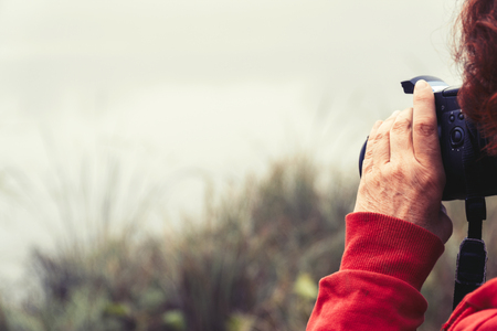 Woman photographer photographs the fog on the lake. Selective focus, blurred backgroundの写真素材