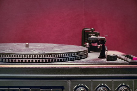 Old record player on red background. Selective focus