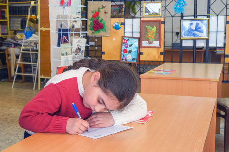 Chapaevsk, Samara region, Russia - May 16, 2019: Elementary school. The girl diligently writes in a...