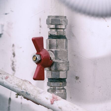 Tap with red handle on white plastic water pipeの写真素材