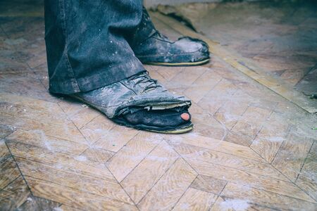 Old torn boots on the mans feet. Boots with holes. Selective focusの写真素材