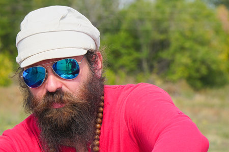 Samara, Russia - August 17, 2019: Portrait of an unfamiliar man in sunglasses, with a beard, in a red shirt and capのeditorial素材