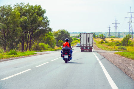 Samara, Russia - August 17, 2019: Biker in a black helmet rides on an asphalt road. Soft focusのeditorial素材