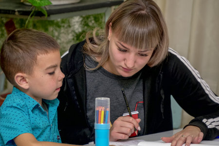 Chapaevsk, Samara region, Russia - October 15, 2019: Elementary school in Chapaevsk. Schoolboy at a desk with a woman teacher. The teacher is engaged with a primary school student. Selective focusのeditorial素材