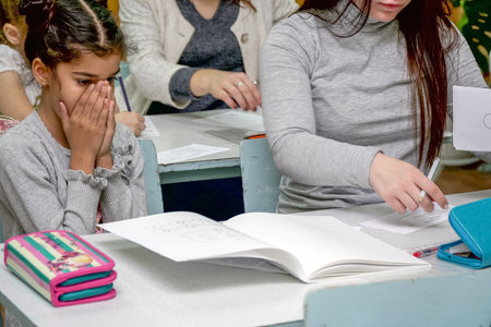 Chapaevsk, Samara region, Russia - October 15, 2019: Elementary school in Chapaevsk. Schoolgirl at a desk with a woman teacher. The teacher is engaged with a primary school Schoolgirl. Selective focusのeditorial素材
