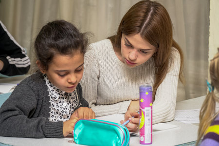 Chapaevsk, Samara region, Russia - October 15, 2019: Elementary school of the city of Chapaevsk. Schoolgirl at a desk with a woman teacher. The teacher is engaged with a primary school Schoolgirl. Selective focusのeditorial素材