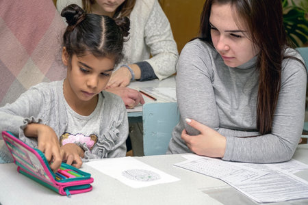 Chapaevsk, Samara region, Russia - October 15, 2019: Elementary school of the city of Chapaevsk. Schoolgirl at a desk with a woman teacher. The teacher is engaged with a primary school Schoolgirl. Selective focusのeditorial素材