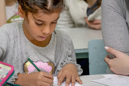 Chapaevsk, Samara region, Russia - October 15, 2019: Elementary school of the city of Chapaevsk. Portrait of a girl in the classroom. Schoolgirl writes in a notebookのeditorial素材