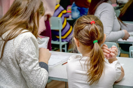 Chapaevsk, Samara region, Russia - October 15, 2019: Schoolgirl at a desk with a woman teacher. The teacher is engaged with a primary school Schoolgirl. Rear view. Selective focusのeditorial素材