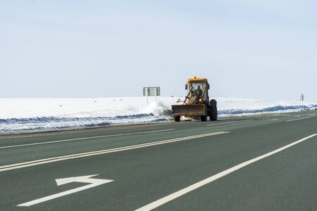 Snowplow cleans the highway from snow on a frosty day