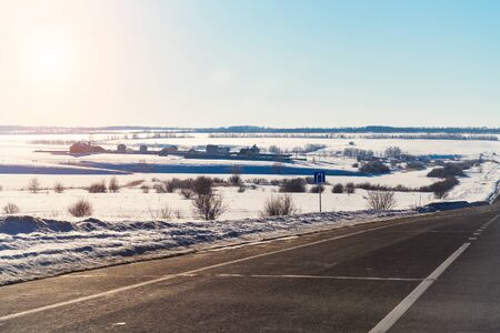Winter road on the background of the sun in the blue skyの写真素材