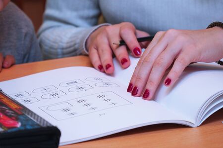 The teacher points a finger at the shapes in the geometry textbook. Selective focusの写真素材