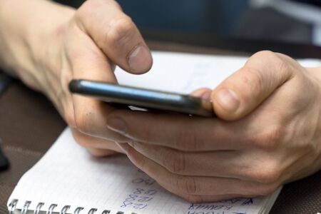 A man holds a smartphone against a sheet of paper