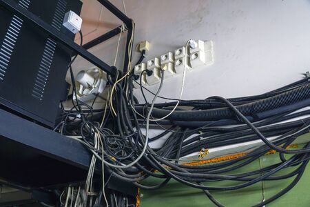 Lots of different cables hanging in a mess on the wall. Poor cable wiring. A jumble of cables