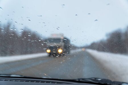 Blurred view through the windshield in the raindrops on the highway, which is moving towards a large...