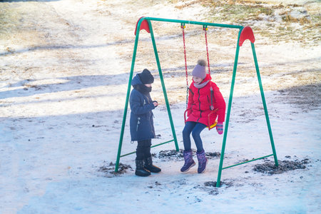 Chapaevsk, Samara region, Russia - December 13, 2019: Two girls on a swing on a winter dayのeditorial素材