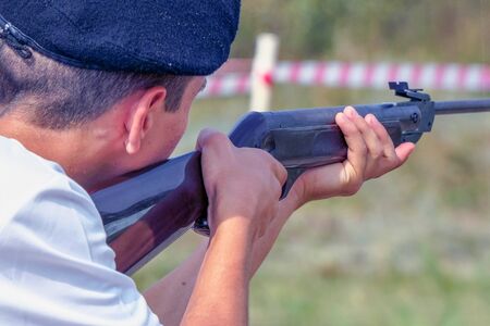 A man in a beret takes aim or shoots with a gun. Back view. Selective focus