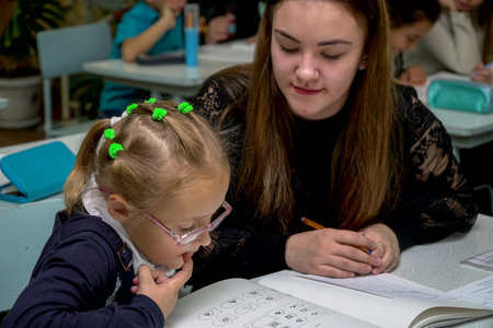 Chapaevsk, Samara region, Russia - October 15, 2019: Schoolgirl in glasses at a desk with a woman teacher. The teacher is engaged with a primary school Schoolgirl. Soft focus. Selective focusのeditorial素材