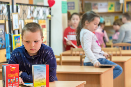 Chapaevsk, Samara region, Russia - May 06, 2019: Elementary school in Chapaevsk. Portrait of a pensive schoolboy in front of books. In the background, you can see the boy's classmate. Selective focusのeditorial素材