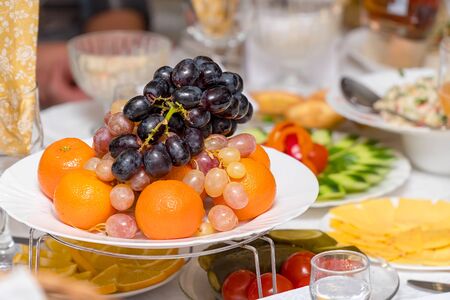 Fruits-grapes, oranges, tangerines, lemon on the holiday tableの写真素材