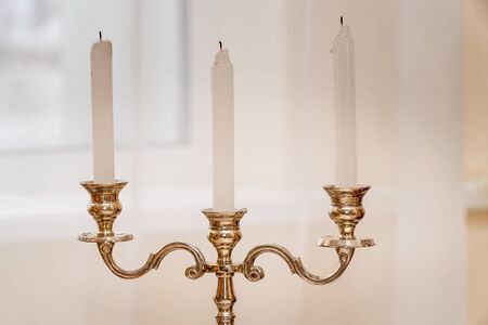 Antique gold candlestick with three candles on a light background