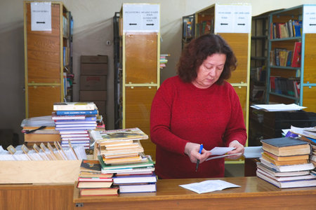 Chapaevsk, Samara region, Russia - Circa April, 2020: Portrait of a woman librarian at a table with...