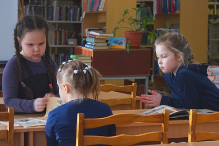 Chapaevsk, Samara region, Russia - Circa February, 2020: Elementary school of the city of Chapaevsk. Little schoolgirls are standing at the desk in the classroom and talking among themselves.のeditorial素材