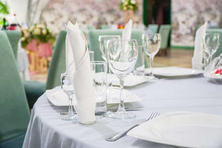 The table in the restaurant is served for dinner. On a table with a white tablecloth, empty wine...