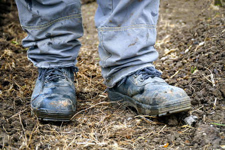 Workers feet in dusty boots. A man in overalls and work boots. Work clothesの写真素材