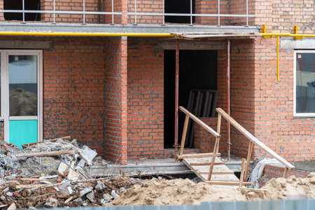 Construction debris next to a red brick house under construction. Garbage on the construction siteの写真素材