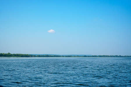 Big river against the blue sky, distant forest and mountainsの写真素材