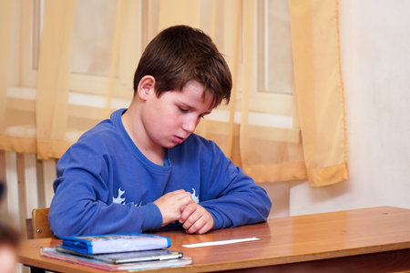 Portrait of a Serious schoolboy sitting at a deskのeditorial素材