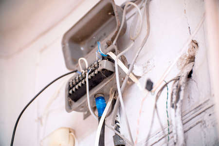 An old junction box with wires on a light wallの写真素材
