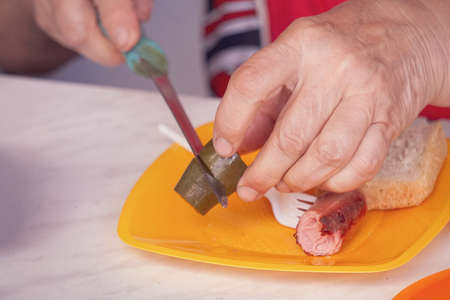 Woman cuts a pickle into slices on yellow plastic plate