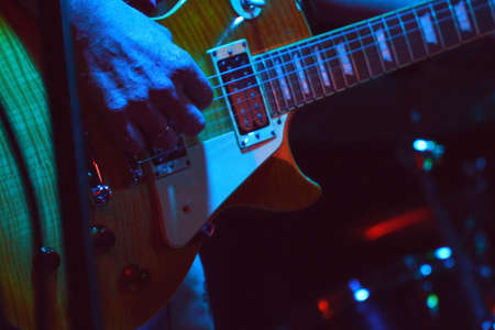 The guitarist plays his guitar in the spotlightの写真素材