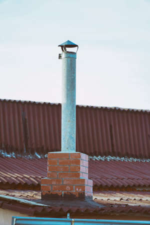 Pipe chimney on the roof against light sky