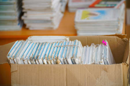 Old battered books in a paper box for putting in waste paper