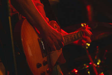 The guitarist plays his guitar in the spotlight. Hands of a guitarist playing the guitar. Low keyの写真素材