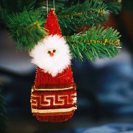 A Santa Claus toy or doll is hanging on the Christmas tree next to the giftsの写真素材