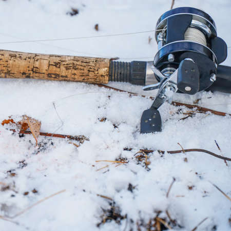 Spinning rod with baitcasting reel lying on the snow in the winterの写真素材