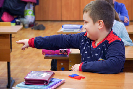 Chapaevsk, Samara region, Russia - July 07, 2021: Elementary school of the city of Chapaevsk. A Schoolboy is sitting at a desk and points to the side with his handのeditorial素材