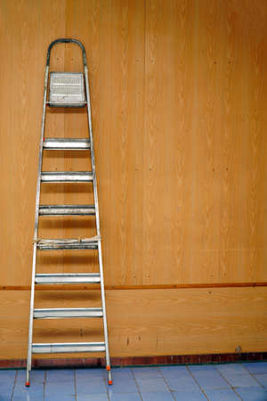A folded aluminum stepladder stands against the wallの写真素材