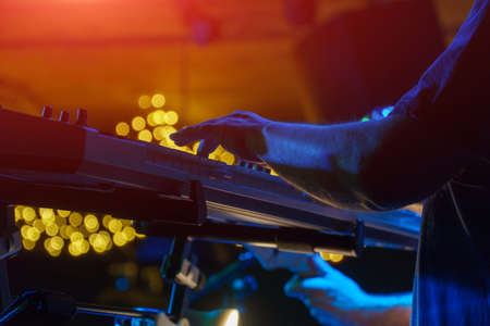 A pianist or keyboardist plays on stage a synthesizer in the spotlight. Dark key. Soft selective focusの写真素材