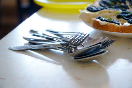 Metal spoons and forks in a pile on the table. Selective focusの写真素材
