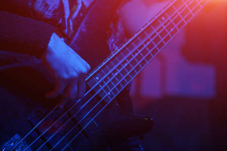 The bass guitarist plays the bass guitar in the spotlight. Selective focusの写真素材
