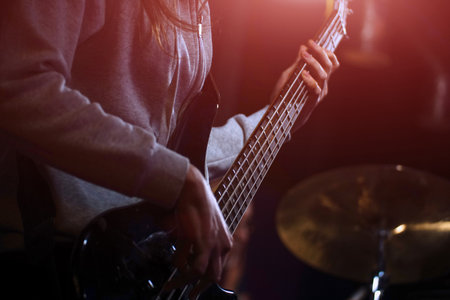 The bass guitarist plays the bass guitar in the spotlight. Selective focus