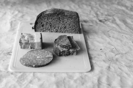 Rye bread, lard and sausage on a cutting board. Rustic natural snack. Selective focus. Black and white photoの写真素材