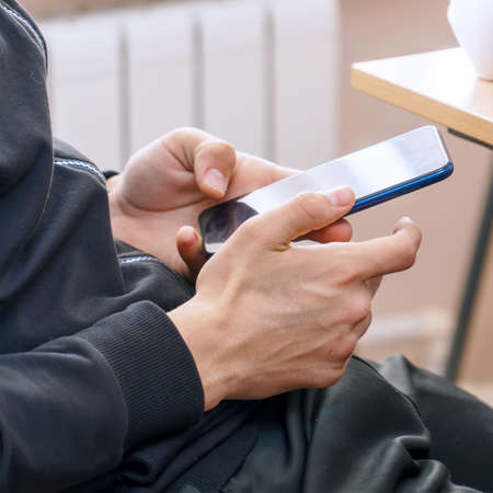 Young Man using a smartphone for texting and communicationの写真素材