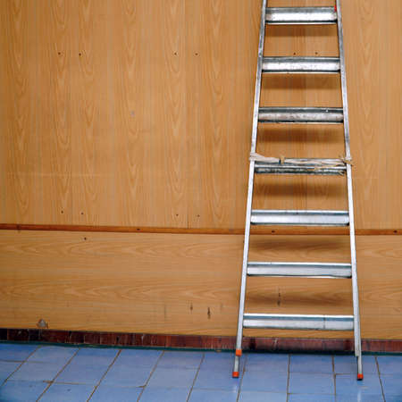 A folded aluminum stepladder stands against the wallの写真素材